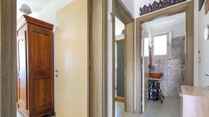 Um corredor com um guarda-roupa de madeira, um espelho e uma pia com cuba.