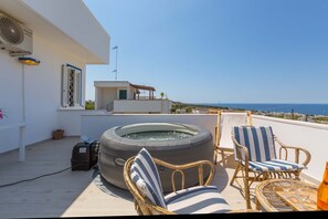 Terraza en la azotea con hidromasaje, sillas de mimbre y vistas al mar.