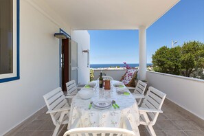 A balcony with a table set for four, overlooking a scenic view.