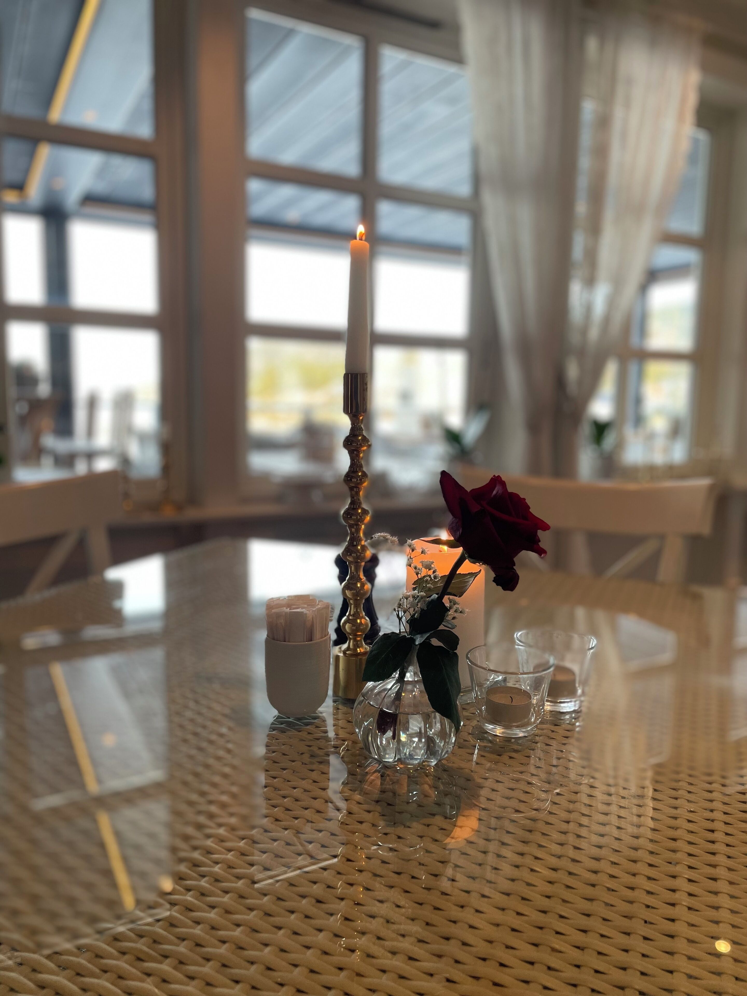 A table with a candle, a vase with a flower, and small glass containers.