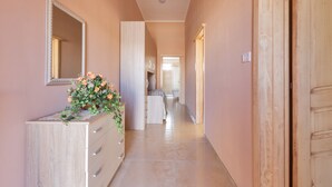 A hallway with a wooden cabinet, a mirror, and a floral arrangement. - 2038 Villetta Gloria (Alliste)