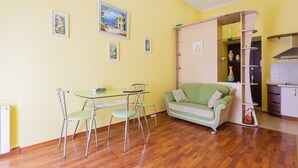 Ein kompakter Wohnbereich mit Essbereich, einem grünen Sofa und einer Küchenzeile.