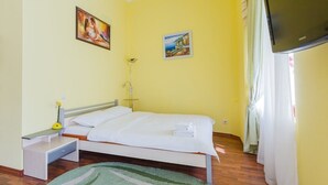 Ein Schlafzimmer mit einem Bett, einem Nachttisch, einer Lampe und einem Flachbildfernseher.