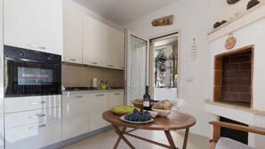 Une cuisine moderne avec des armoires blanches, un four encastré et un coin repas où une table est dressée pour le repas.
