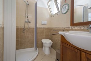 A bathroom with a shower, toilet, and sink.