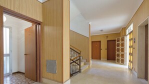 A spacious hallway with wooden paneling, a staircase with a metal railing, and a door with a glass panel. - 2251 Appartamento Sara by Barbarhouse (Gallipoli)
