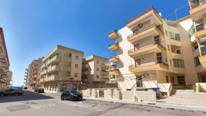 A residential street with multi-story buildings, a stop sign, and cars parked along the road. - 2251 Appartamento Sara by Barbarhouse (Gallipoli)