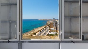 A view from a window overlooking a coastal area with buildings, a beach, and the sea. - 2016 Attico Bellavista (Gallipoli)