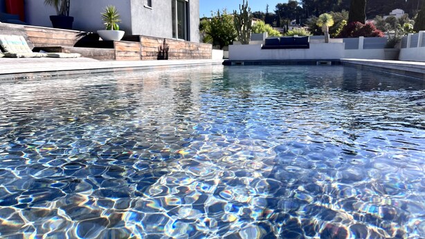 Ein klares Schwimmbecken mit einem modernen Haus im Hintergrund.