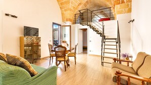 Amplia sala de estar con techo de piedra alto, una escalera, comedor y sofá.