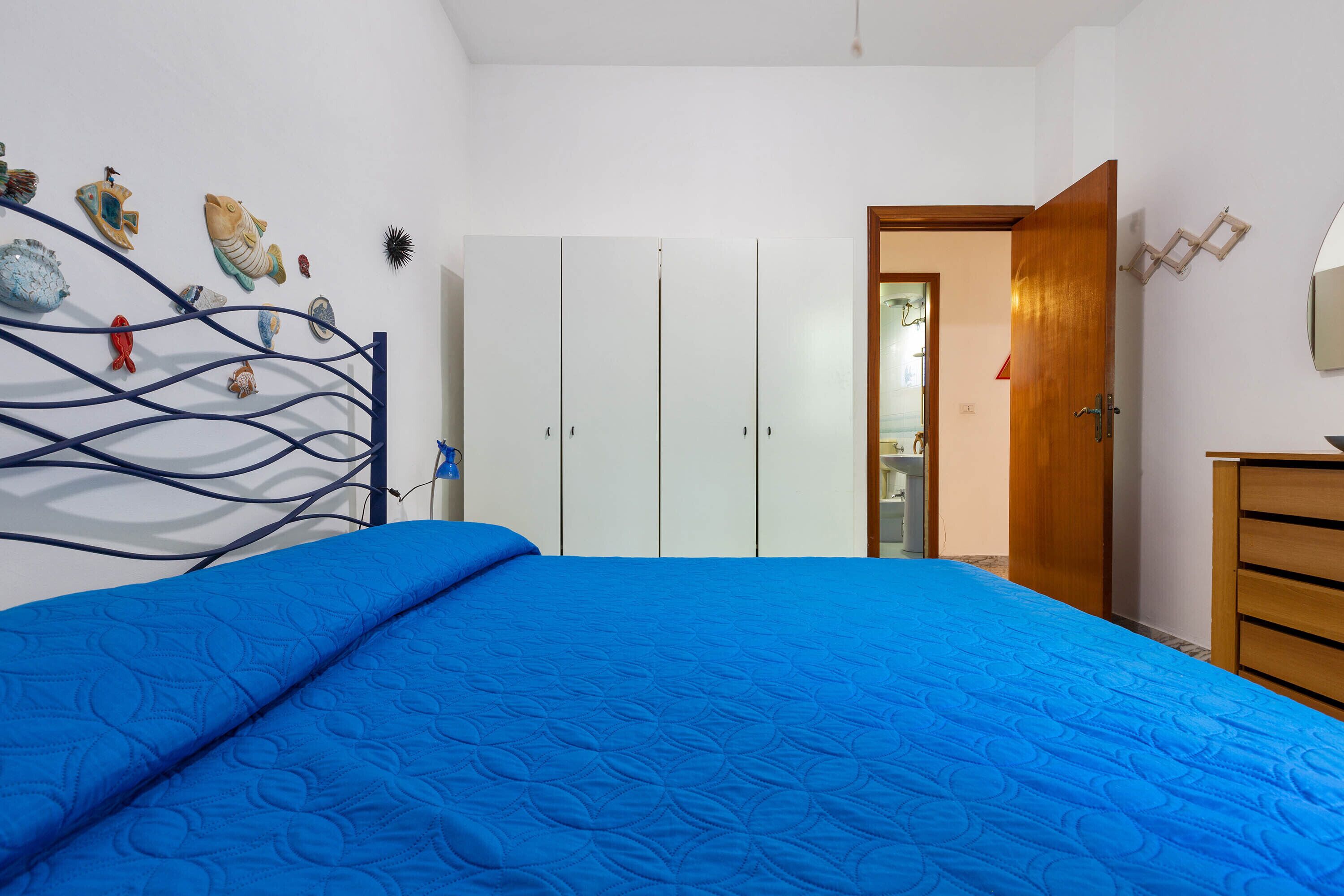 A bedroom with a bed, wardrobe, and wall decorations.
