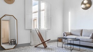 A modern living room with a sofa, a coffee table, a standing mirror, and a large window. - 2239 Salento Sunset (Matino)