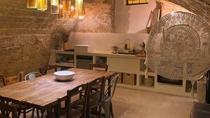 A rustic dining area with a wooden table and chairs, a bowl on the table, and hanging pendant lights. - 2239 Salento Sunset (Matino)