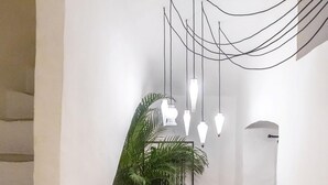 A staircase with a potted plant, a framed artwork, and a hanging light fixture. - 2239 Salento Sunset (Matino)
