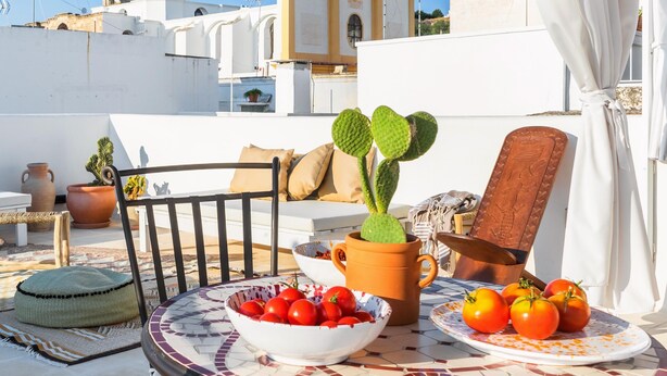 A rooftop terrace with a table set with tomatoes, a cactus, and a bowl of cherries. - 2239 Salento Sunset (Matino)