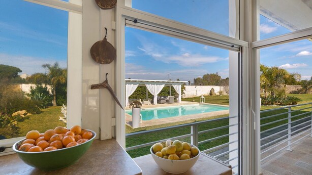 A balcony with a view of a swimming pool, a bowl of oranges, and a bowl of lemons. - Villa Padangi (Gallipoli)