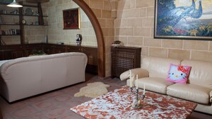 A living room with a beige sofa, a coffee table with candles, and a painting of birds on the wall. - 2099 Villa Arkè (Alliste)