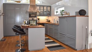 A modern kitchen with grey cabinetry, stainless steel appliances, and a central island with bar stools. - Stunning home in Sölvesborg with WiFi (Sölvesborg)