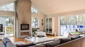 A modern living room with a large sectional sofa, a fireplace, a television, and a dining area with outdoor seating. - Stunning home in Sölvesborg with WiFi (Sölvesborg)