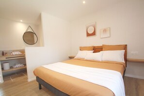 Une chambre à coucher comprenant un lit, une table de chevet, un miroir et une étagère fixée au mur.