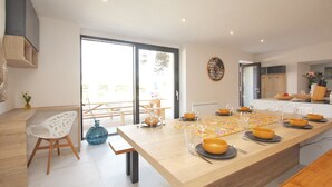 Une cuisine moderne avec une grande table à manger dressée pour six personnes, agrémentée de bols jaunes et de verres à vin.