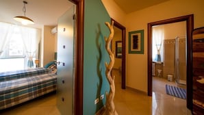 Una habitación con una cama, una escultura de madera y un baño visible a través de una puerta abierta.