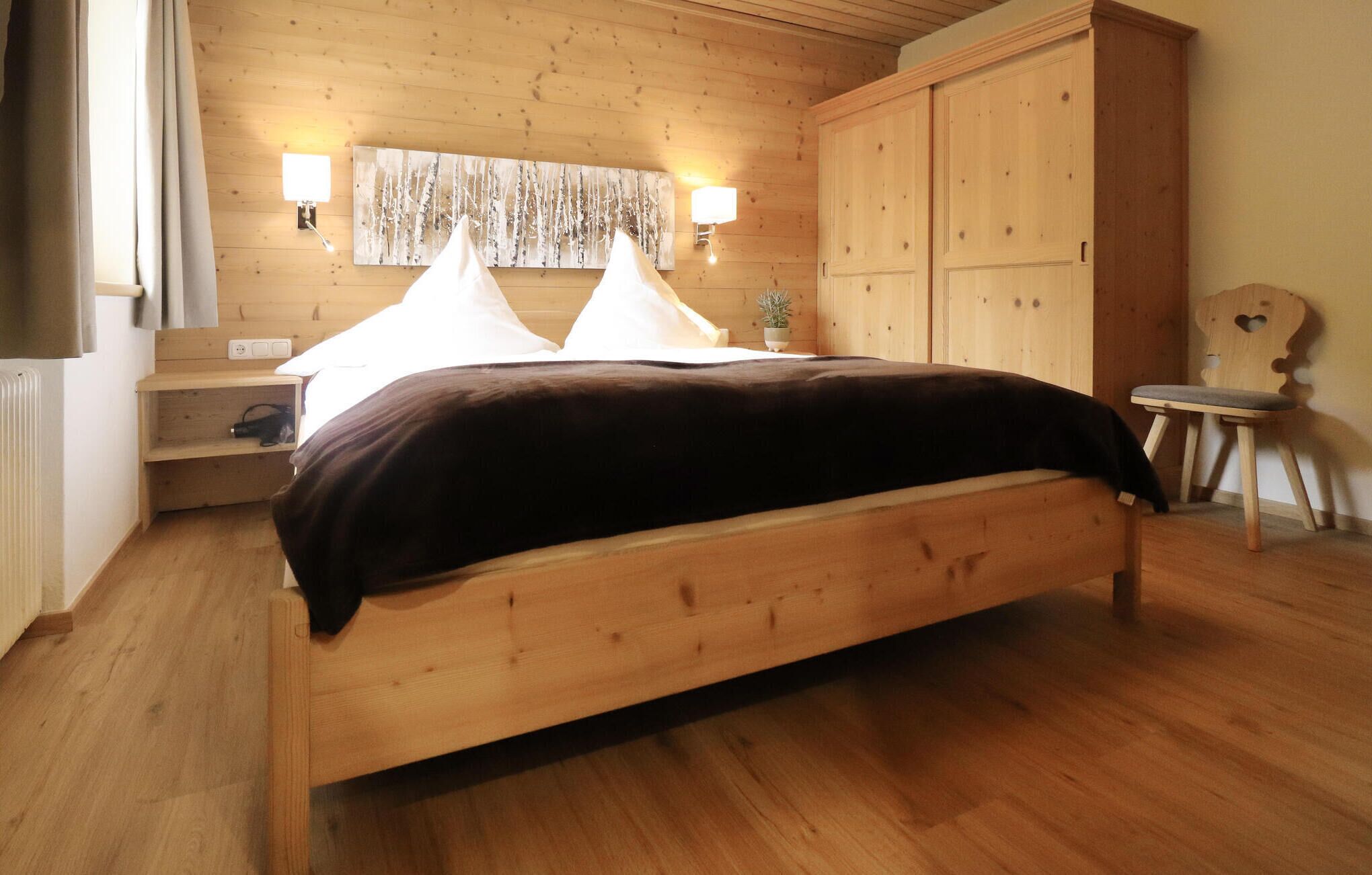 Ein hölzernes Bett mit dunkelbrauner Kopfteil in einem Zimmer mit Holzwänden und Holzböden.
