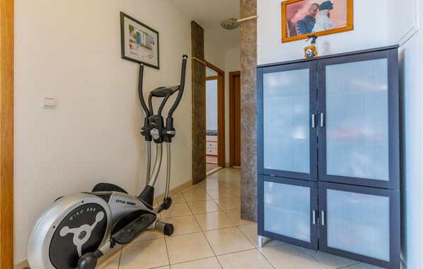 A hallway with a stationary exercise bike, a cabinet with frosted glass doors, and a framed picture on the wall. - 3 bedroom nice apartment in Duce (Duce)
