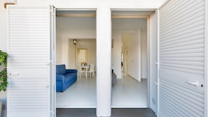 A modern interior with a dining area, a blue sofa, and a kitchen visible through open doors. - 2103 Villetta Clara (Nardò)