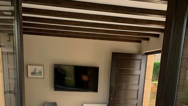 Un balcón con cama, televisor, silla y radiador.