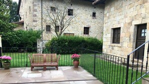 Un edificio de piedra con un banco de madera y plantas en macetas en un patio empedrado.