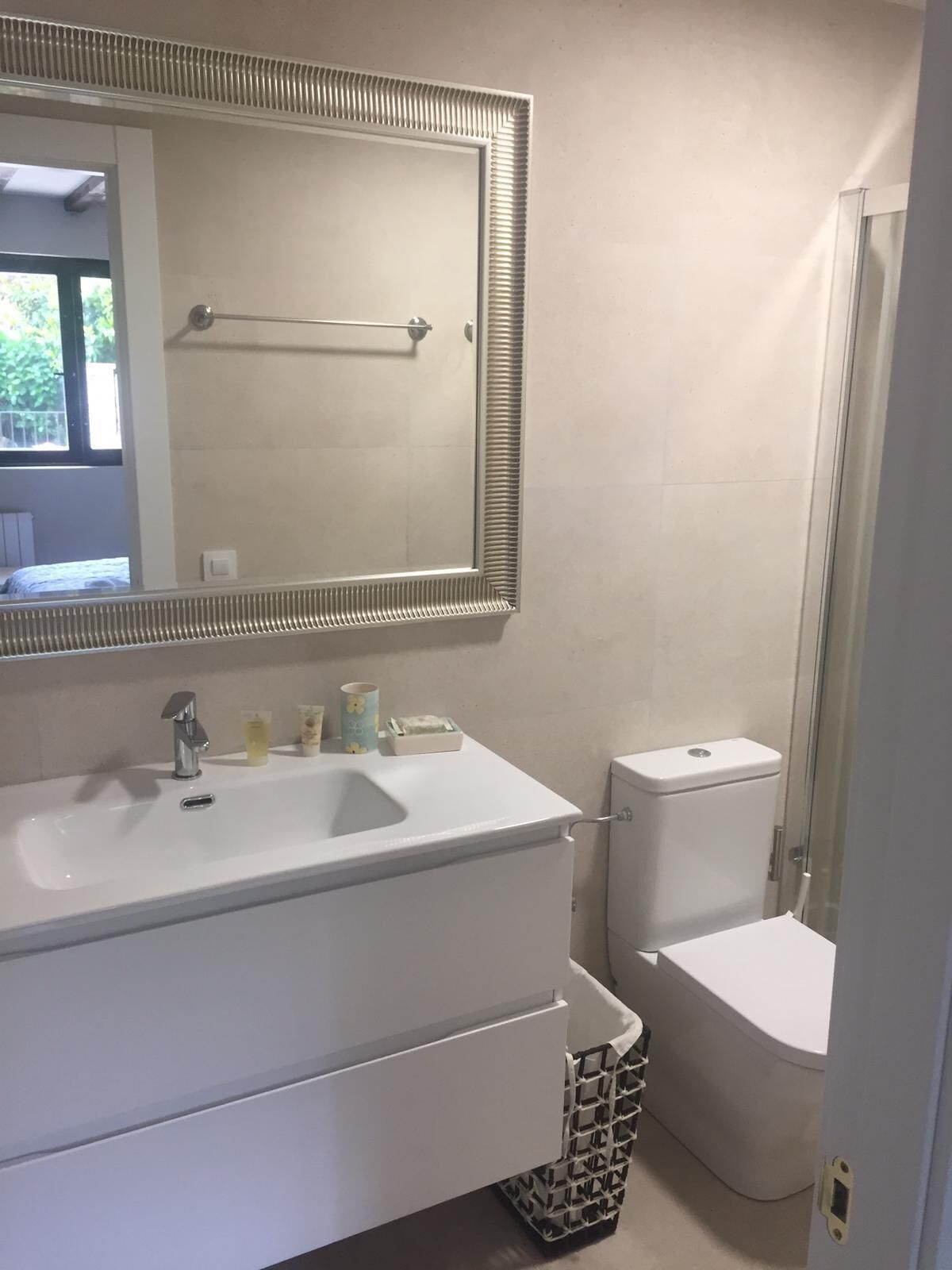 A bathroom with a white sink, a mirror, a toilet, and a shower.
