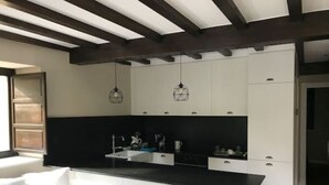 Una cocina moderna con armarios blancos, encimera negra y luces colgantes.