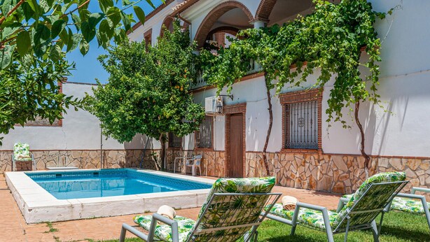 Une piscine avec deux chaises longues et un mur en pierre.
