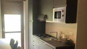 Een moderne keuken met grijze kastjes, een zwart aanrecht, een ingebouwde magnetron en een gasfornuis.