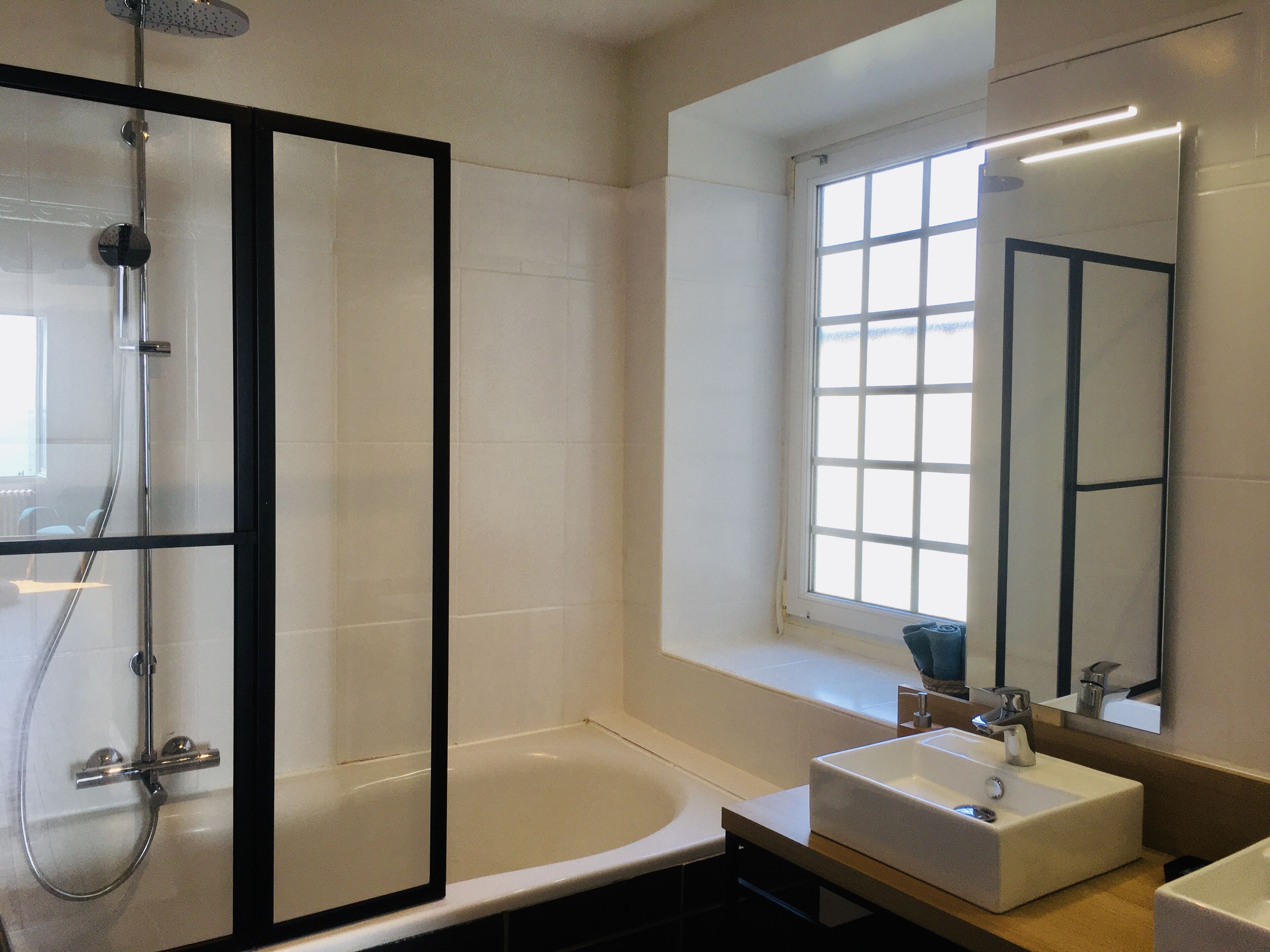 Une salle de bain moderne avec une douche à parois de verre, une baignoire et un lavabo surmonté d’un miroir.