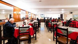A restaurant with multiple tables and chairs, a wooden interior, and a television screen on the wall. - Ayenda 1066 Virrey Centro (Bogotá)