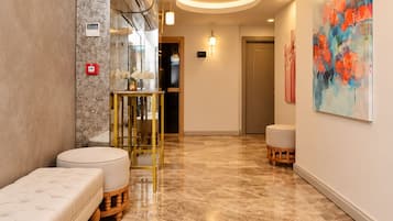 Un hall d’hôtel avec un sol en marbre, un espace salon et un tableau accroché au mur.