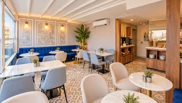 Un espace repas moderne avec des tables rondes, des sièges rembourrés en tissu bleu et un sol à motifs.