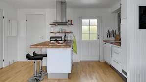 Eine Küche mit weißen Schränken, einer Holz Arbeitsplatte, einem eingebauten Herd und einem Fenster.