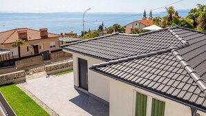 En bostadsbyggnad med ett tak täckt av tegelpannor, ett väl synligt fönster och utsikt över havet.