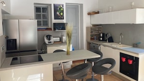 Een moderne keuken met roestvrijstalen apparatuur, een centraal eiland met barstoelen en een magnetron boven de gootsteen.