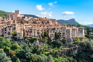 Un pueblo histórico con edificios de piedra, construcciones escalonadas y montañas al fondo.