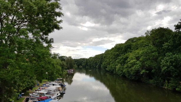 A river with boats docked along the bank, surrounded by dense greenery. - Wunderschöne Ferienwohnung (Brandenburg an der Havel)