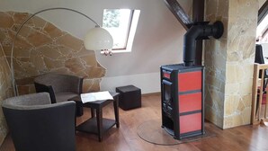 A cozy room with a stone wall, a black sofa, a small table, and a red and black fireplace. - Wunderschöne Ferienwohnung (Brandenburg an der Havel)