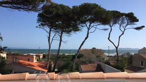 Two glasses of white wine on a balcony overlooking a coastal view with buildings and trees. - Maison VUE MER 50M DE LA Plage A Pied (Hyères)