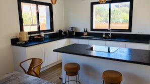A modern kitchen with a large island, two bar stools, and a dining table. - Maison VUE MER 50M DE LA Plage A Pied (Hyères)