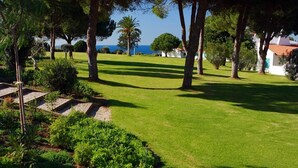 Un jardín cuidado con césped, árboles y un sendero de piedra que conduce a un edificio.