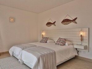 A bedroom with a large bed, two wall-mounted lamps, and two fish-shaped wall decorations. - Aldeamento Da Prainha (Portimao)