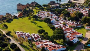 Una zona residencial costera con edificios blancos, césped verde y acantilados rocosos.